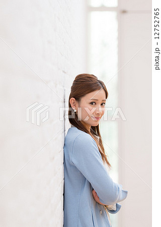 腕組み 寄りかかる 女性 壁の写真素材