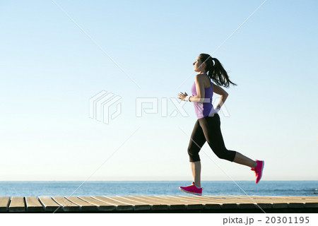 Side view of attractive and healthy fitness woman running along