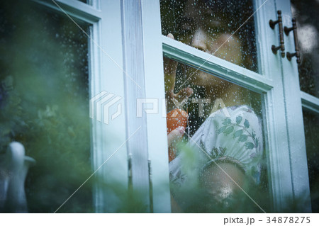 女性 雨 雨の日 窓越しの写真素材