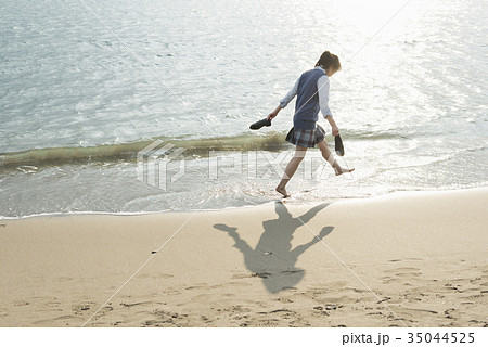 海 夕焼け 女の子 波打ち際の写真素材
