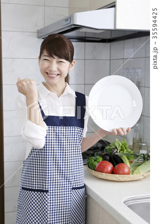 女性 エプロン姿 白い皿 ガッツポーズの写真素材