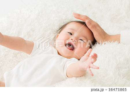 女性に撫でられる赤ちゃん 笑顔 の写真素材