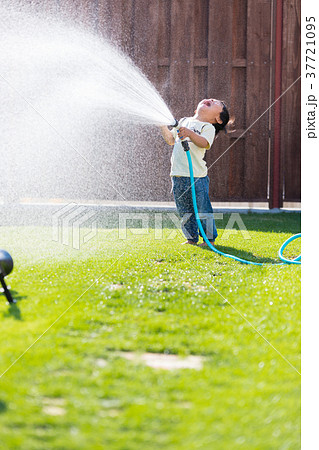 子供 水 水遊び ホースの写真素材