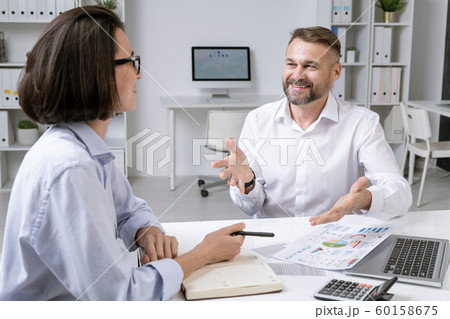 Happy mature broker and his young female colleague discussing financial papers