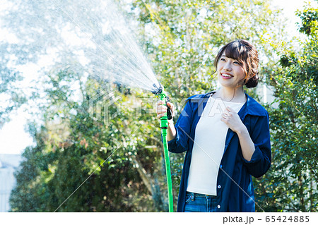 女性 庭 ホース 水やりの写真素材 女性 庭 ホース 水やりの写真素材