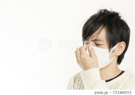 マスク姿の男性/頭痛で頭を抱える/具合が悪い独身男性/	