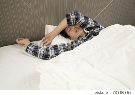 寝起きに発熱がわかり、体調が悪くなって会社に行けないパジャマ姿の男性	