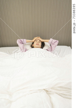 病気で寝込んでいる女性/体調の悪い女性/ベットに寝ている美しい女性