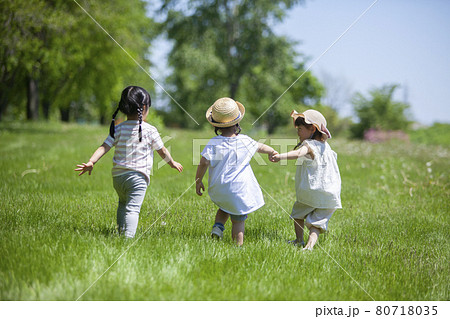 女の子 草原を走る子供 後ろ姿の写真素材