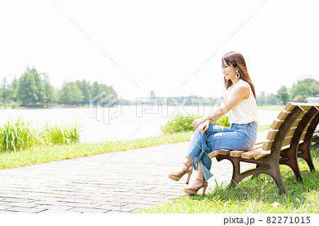 女性 公園 ベンチ 座るの写真素材