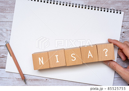 「NISA」と書かれた積み木、ペン、ノート、手