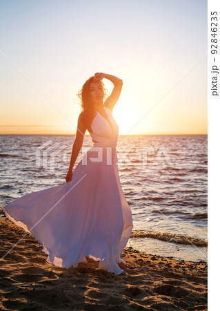 女の子 白いワンピース 海 風の写真素材